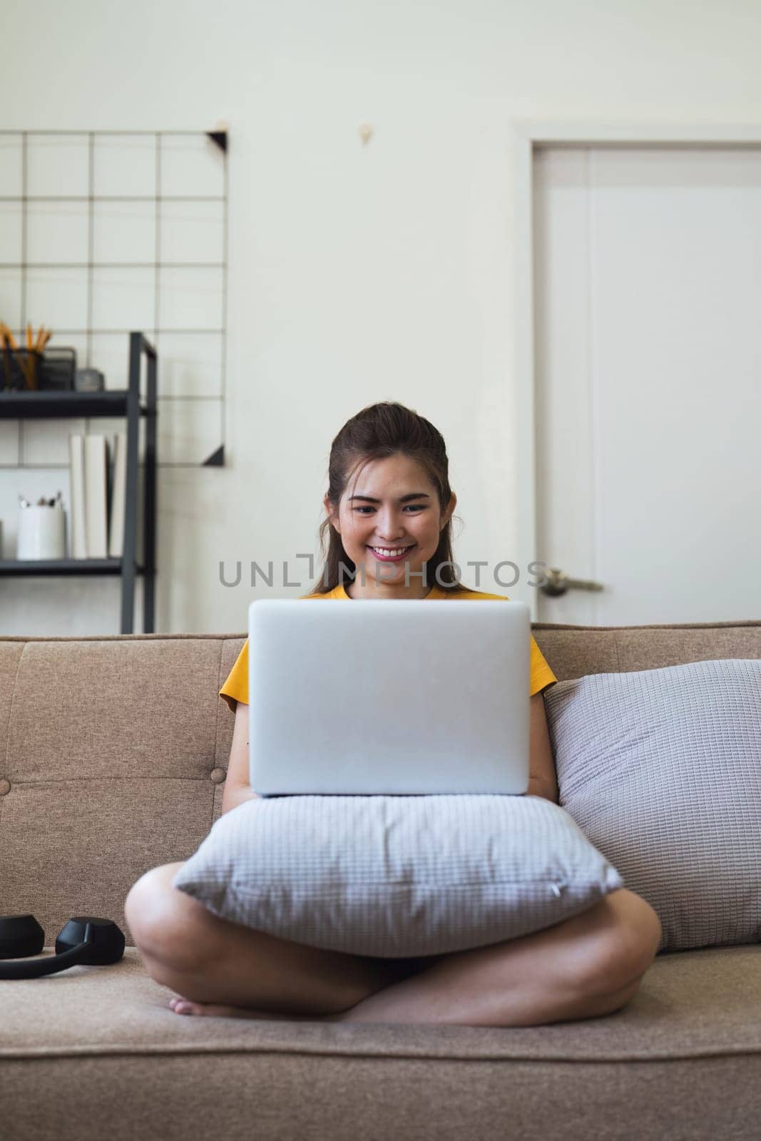 Young woman Asian using laptop pc computer on couch relax surfing the internet at home. lifestyle relaxation concept by nateemee