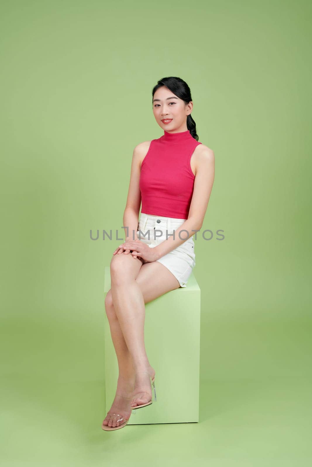 A seated young smiling business woman against green background