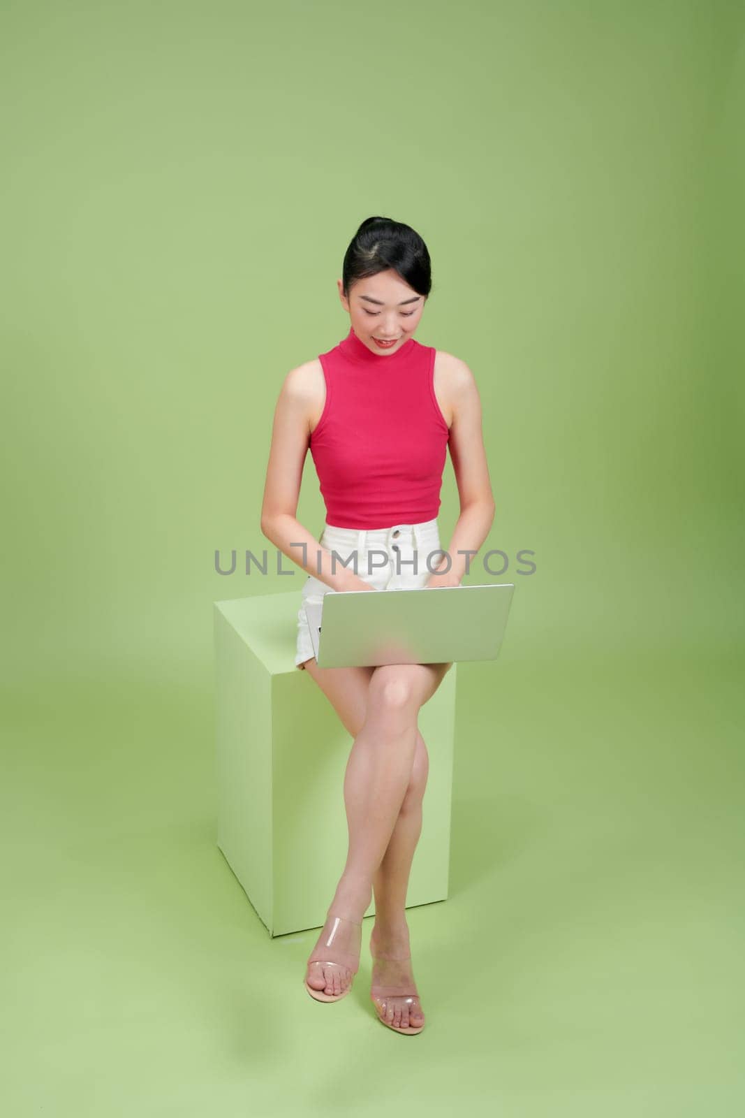Young girl with a laptop sitting on a box stool