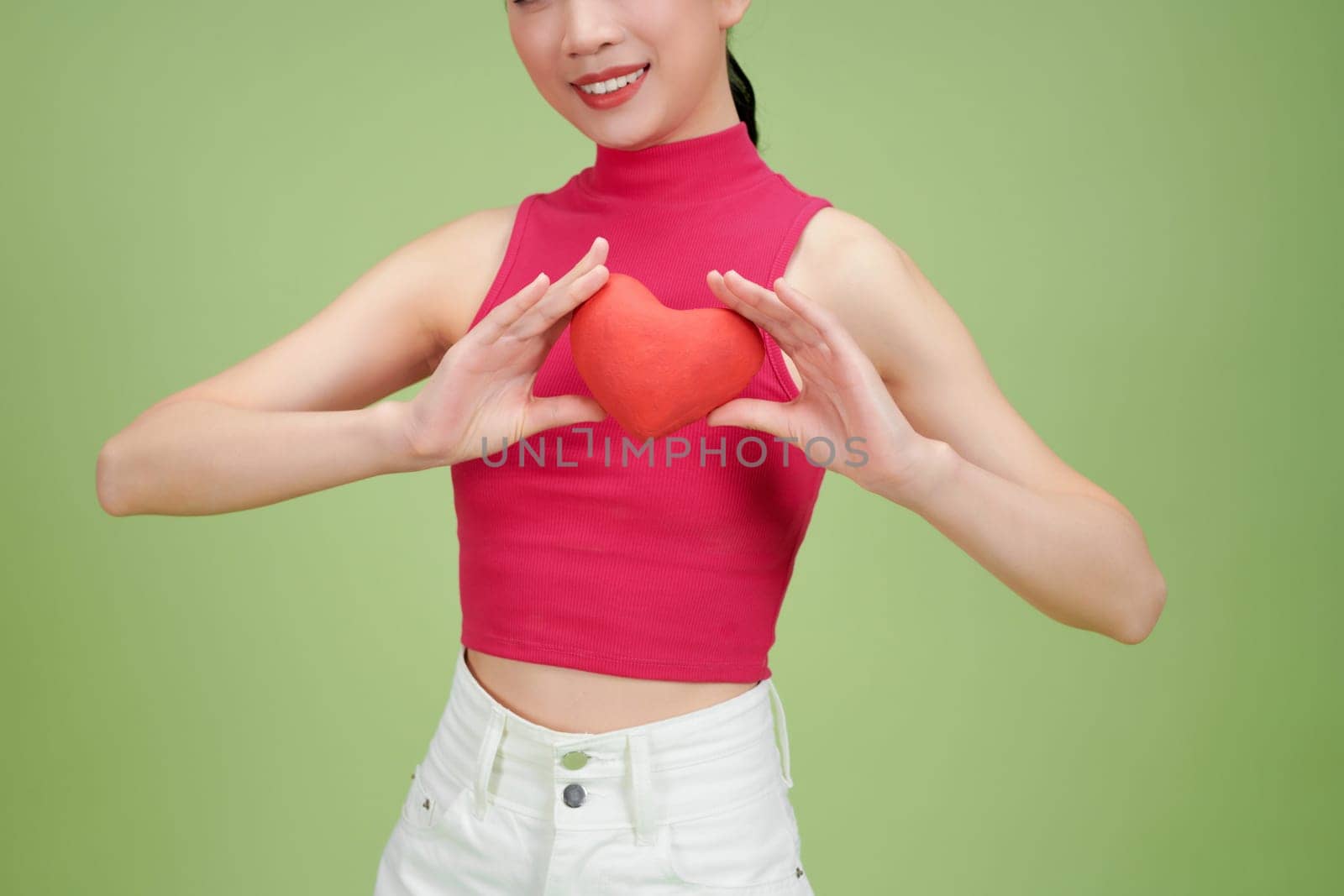 Love and valentines day woman holding heart smiling cute and adorable isolated on green background by makidotvn