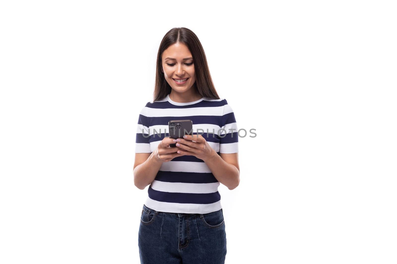 young brunette european lady of slim build dressed in a striped summer t-shirt chatting on a smartphone.