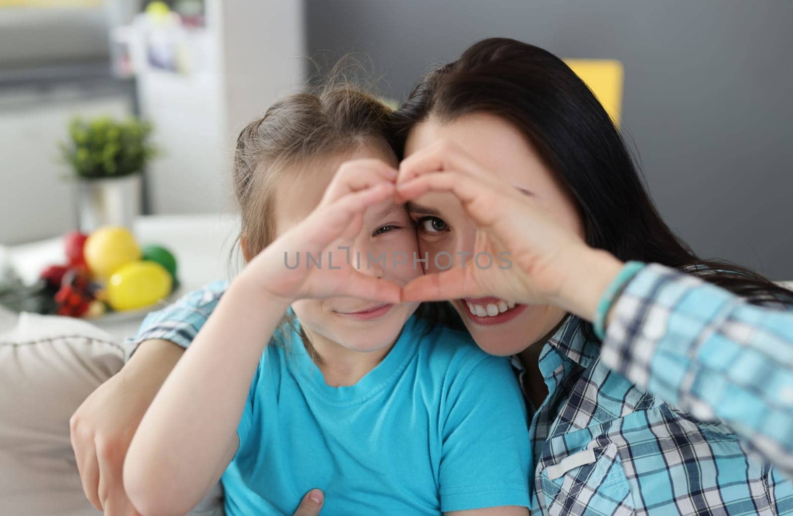 Little girl and mother hugging and showing heart together with their hands by kuprevich