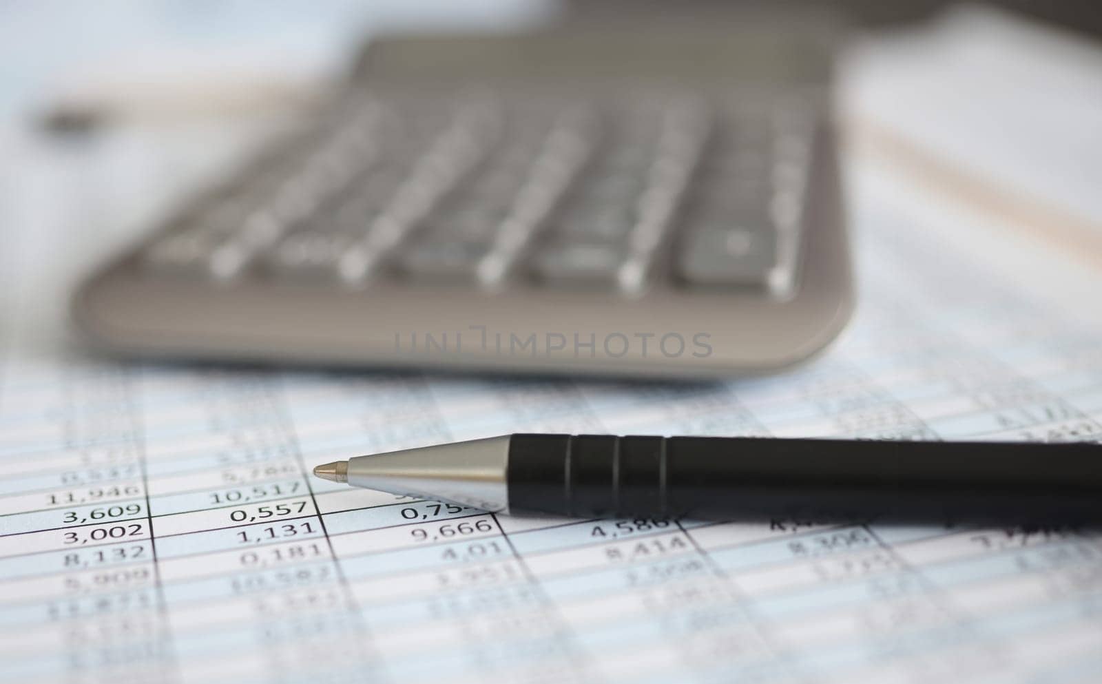 Calculator and ballpoint pen lying on document with numbers closeup. Accounting education concept