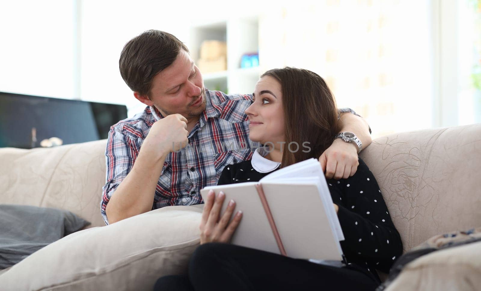 Portrait of smiling young beautiful woman reading interesting book. Middle-aged man embrace and looking on female. Lovely happy couple. Education and spare time concept