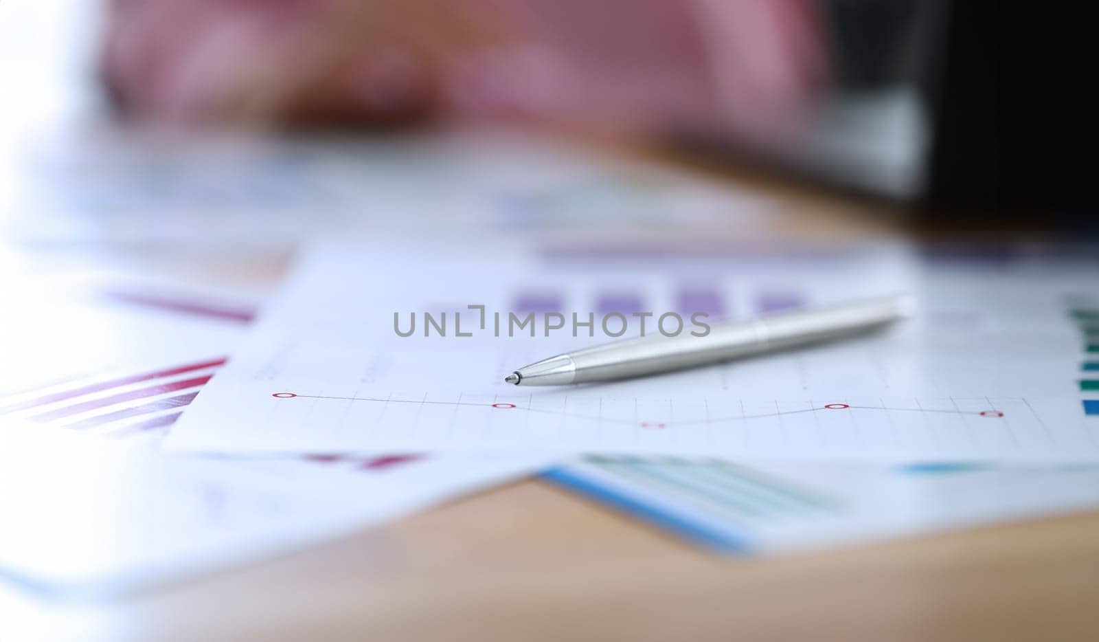 Close-up of silver pen laying on business papers. Working desktop with documents. Diagrams and graphs. Financial company. Statistics report. Economy and finance concept