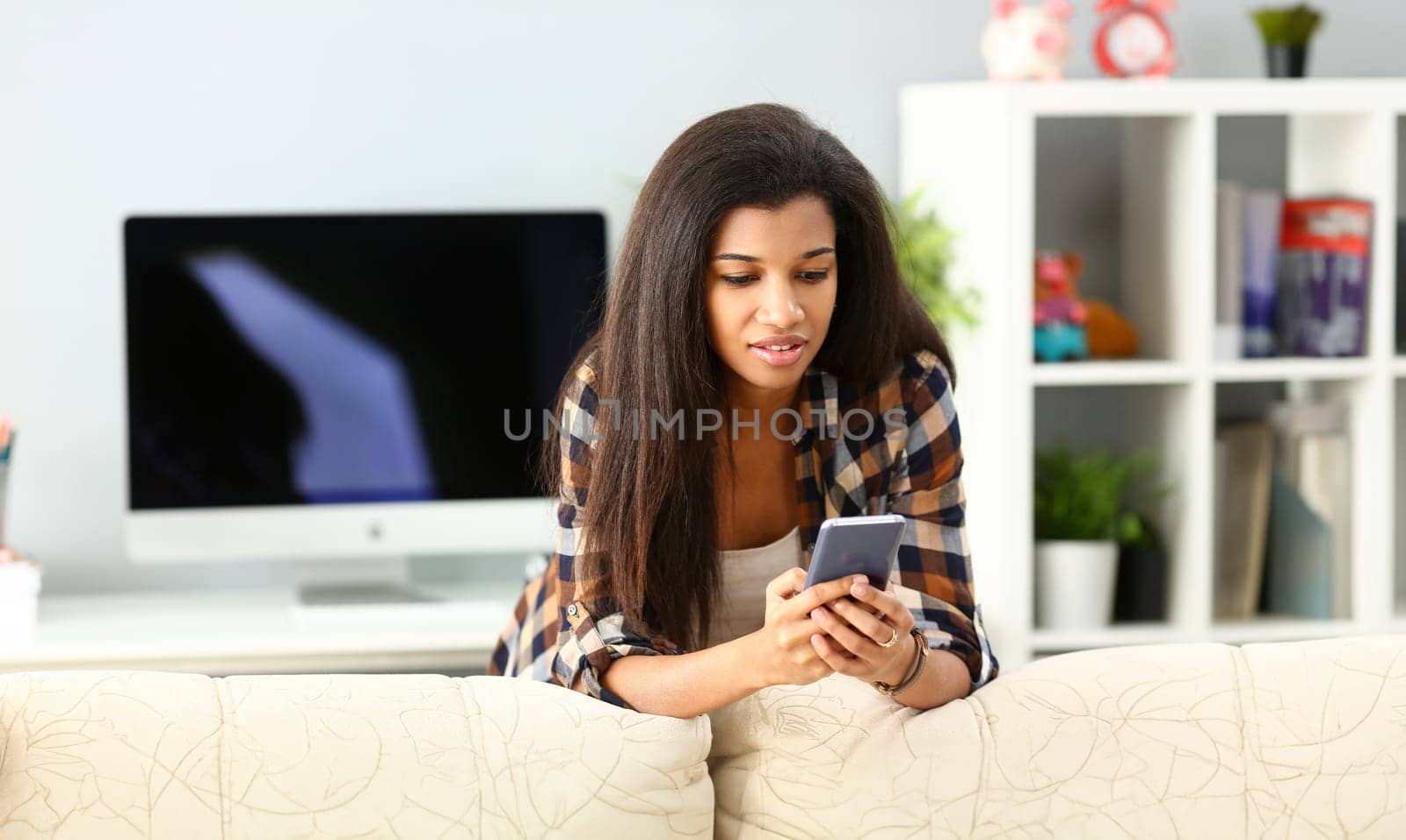 Smiling black woman hold in hand mobile phone at home using video chat service