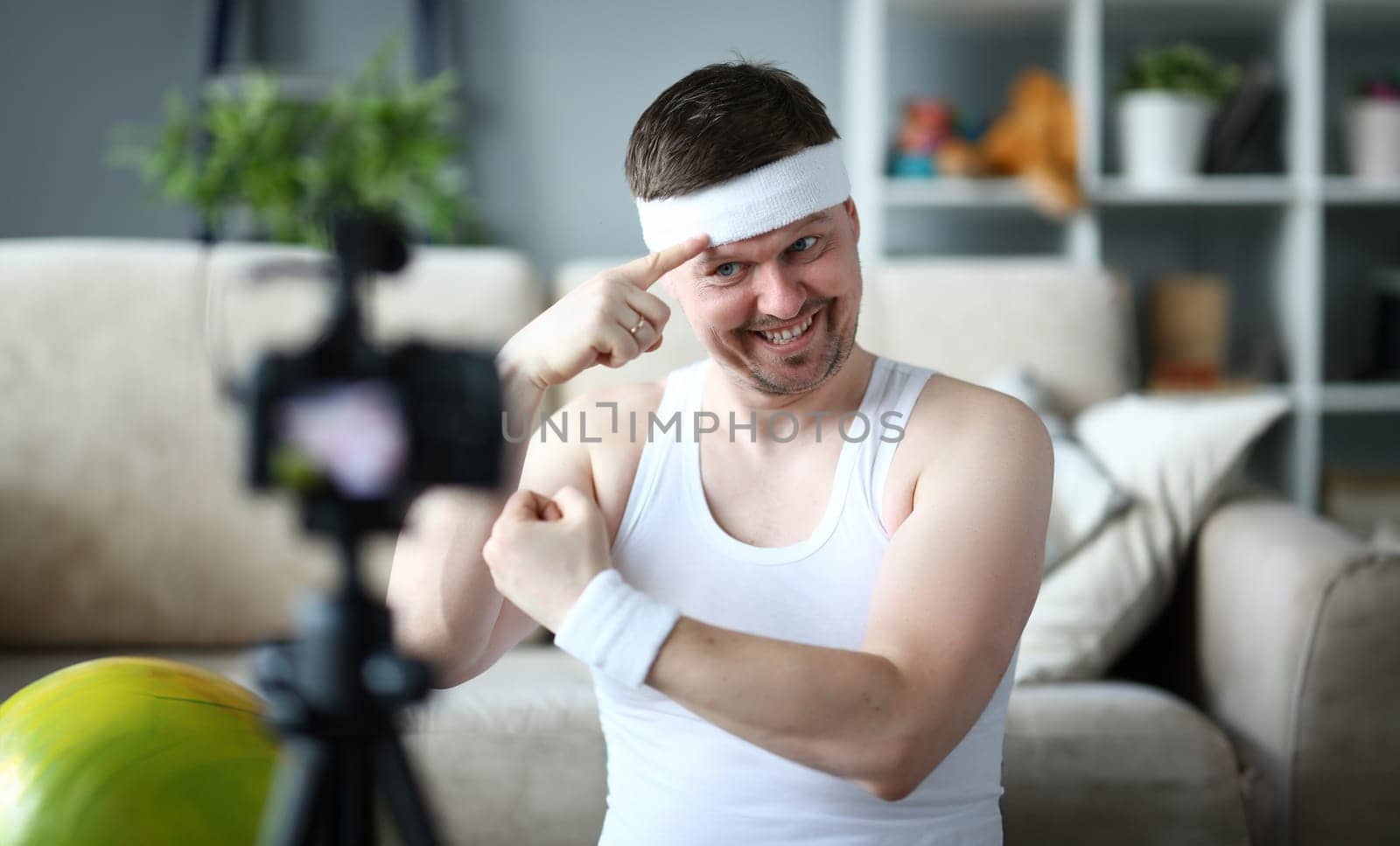 Smiling Vlogger Show Muscle on Digital Camera. Beard Man Demonstrate Muscle on Hands. Sportsman Recording Video on Professional Camcorder for Sport Vlog. Happy Male Shooting Fitness Exercise at Home
