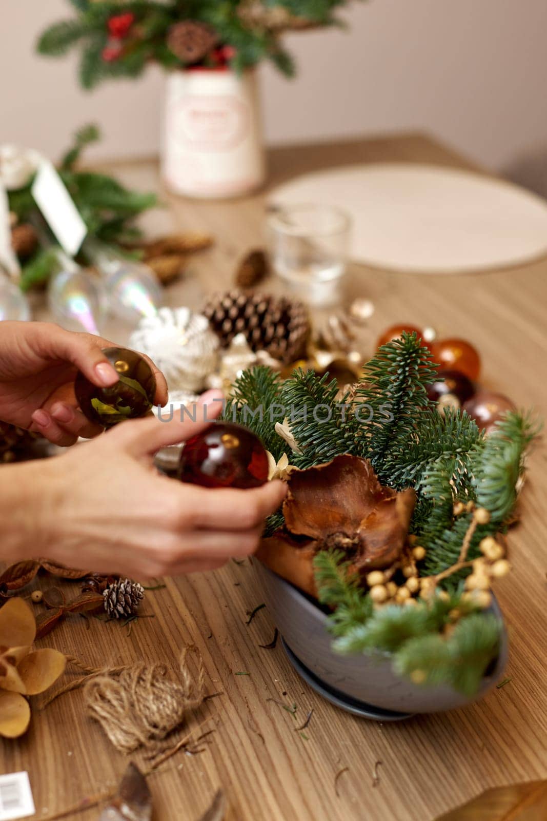 Female hands creating Christmas craft handmade decor with fir branches and dried flowers