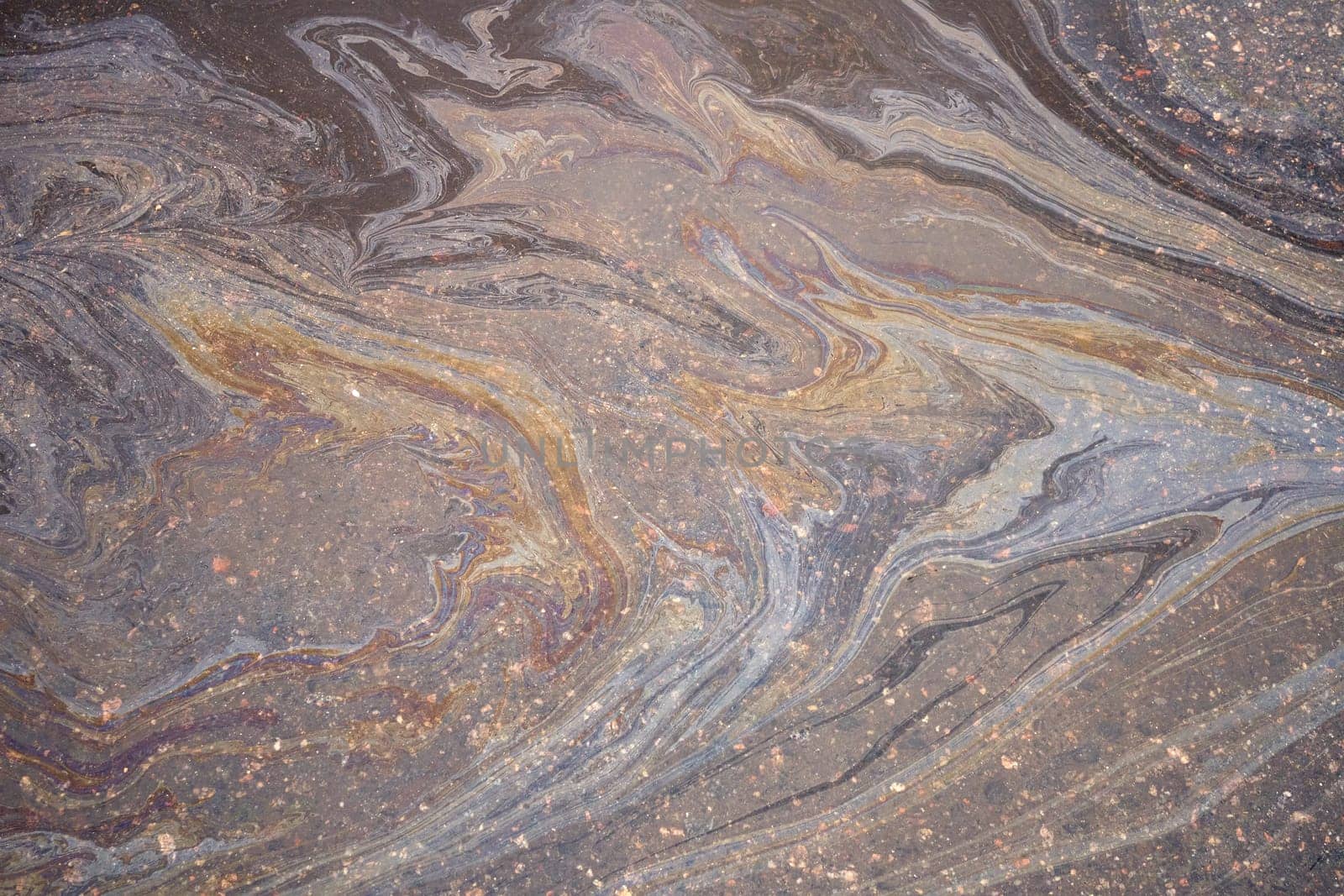 Oily film of rainbow oil or gasoline spill on the surface of a puddle, top view. Environmental problems concept