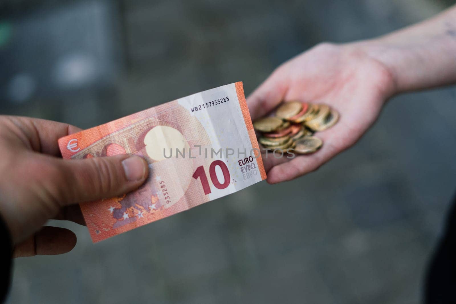 Close-up of a hand giving coins to another hand with banknotes by Zelenin