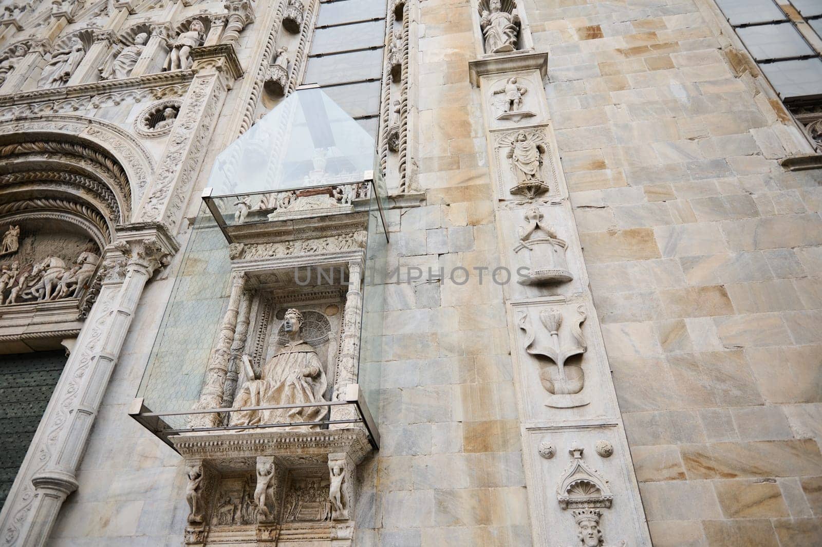 Exterior of the Cathedral in the city of Como, with Italian architectural details, sculpture, stone carvings, covered with a protective glass structure from external influences. Lombardy. Italy