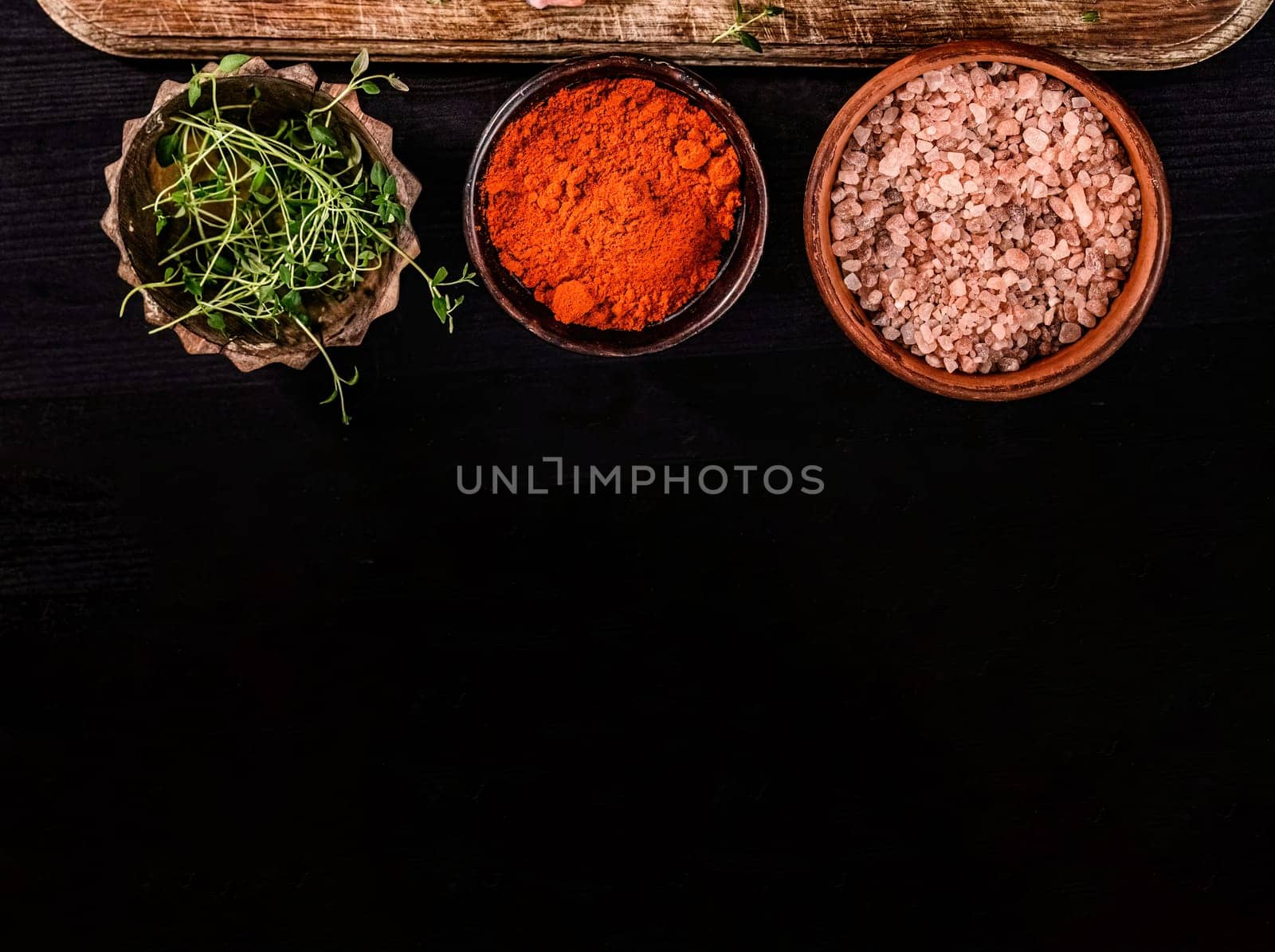 helps spices and salt in bowls on a black table, top view with copy space