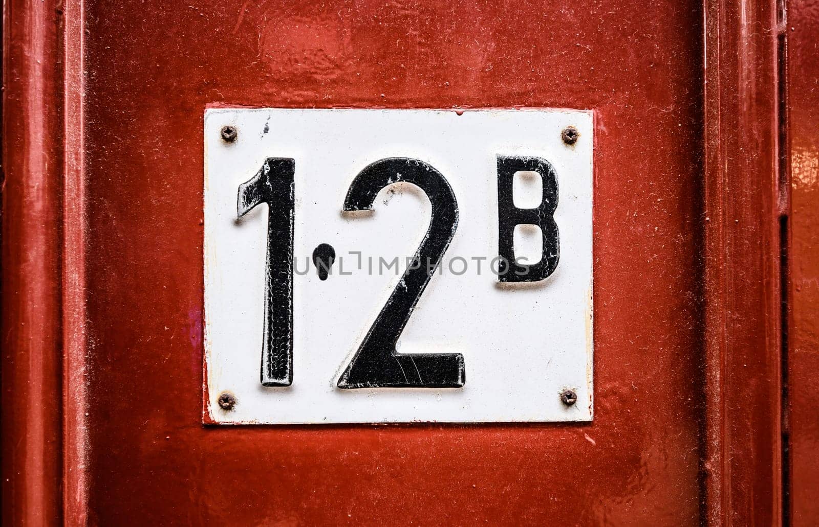 Address sign on residential building wooden door with apartment number twelve. House identification signboard