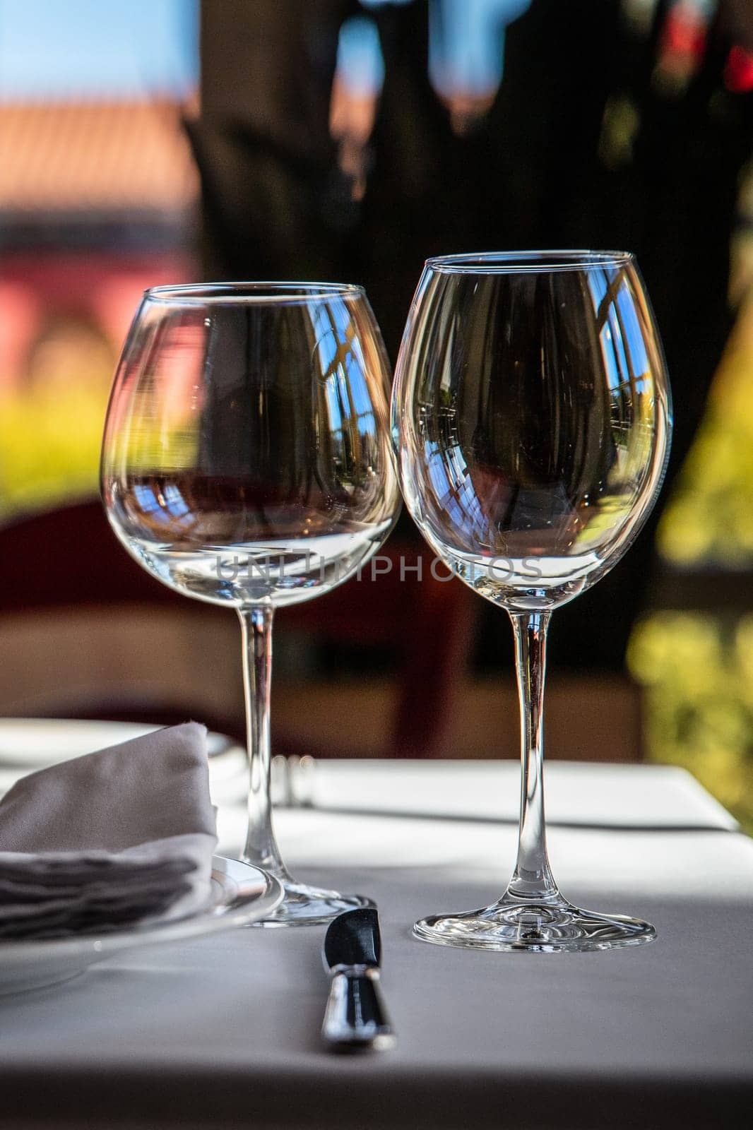 2 wine glasses for different types of wine stand on a served dining table in a luxury restaurant by Rom4ek