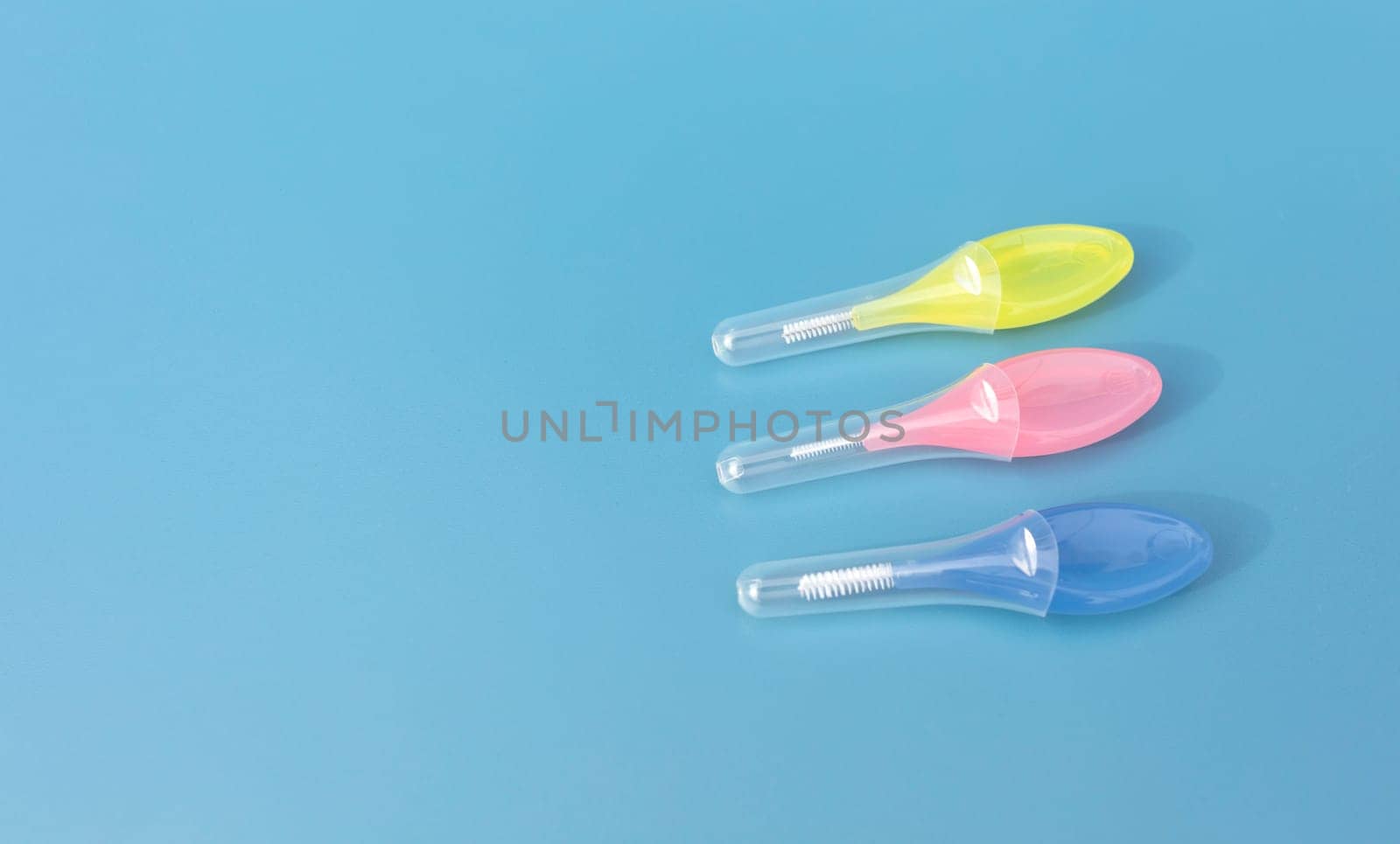 Mockup Colorful Interdental Toothbrush For Cleaning Between Teeth On Blue Background . Toothpick With Soft Bristles, Oral Tooth Cleaning Tool. Horizontal, Copy Space For Text. Dental And Orthodontic.