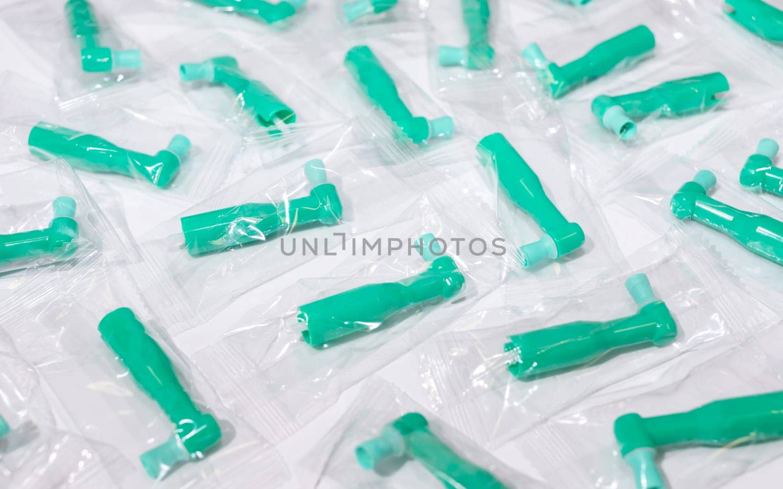 Many Green Disposable Prophy Angles with Brush, Ergonomic Shape on White Background. Dentistry, Orthodontic Product. Oral Hygiene. Horizontal Plane by netatsi