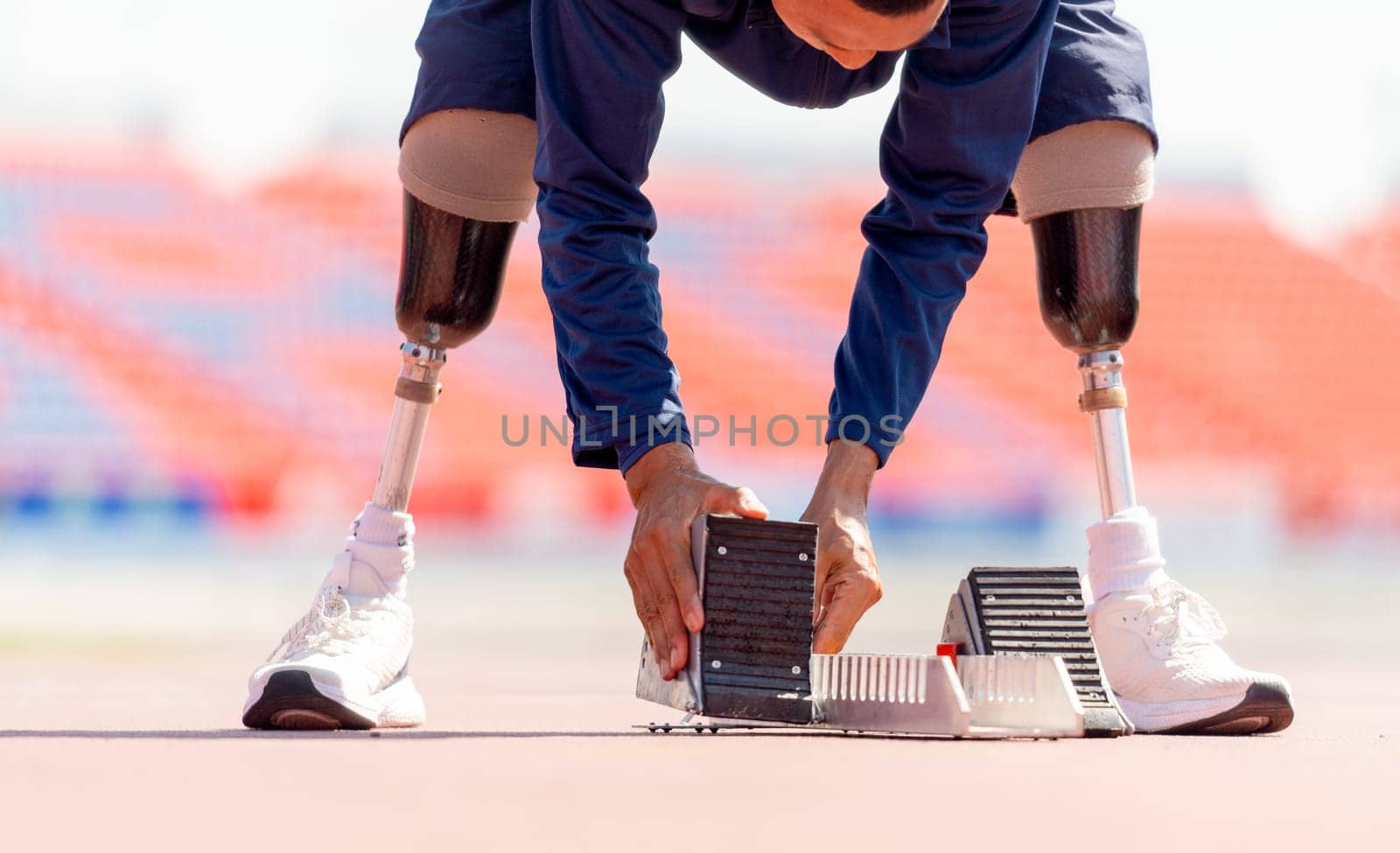 Close up sport man athlete with a prosthesis on his leg prepare of the running equipment on the track at the stadium. Sport concept.