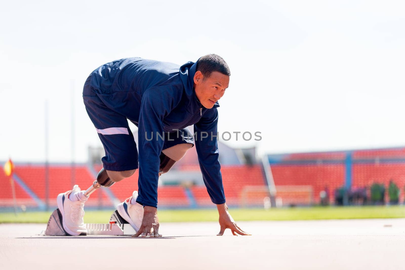 Side view of sport man athlete with a prosthesis on his leg action of start to run on the track at the stadium. Sport concept.