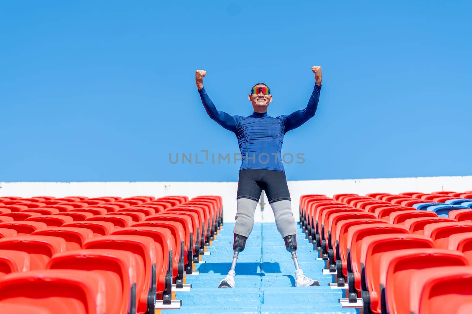 Sport man athlete prosthesis legs stand on stairs with action of happy and celebration on amphitheater in the stadium with day light.