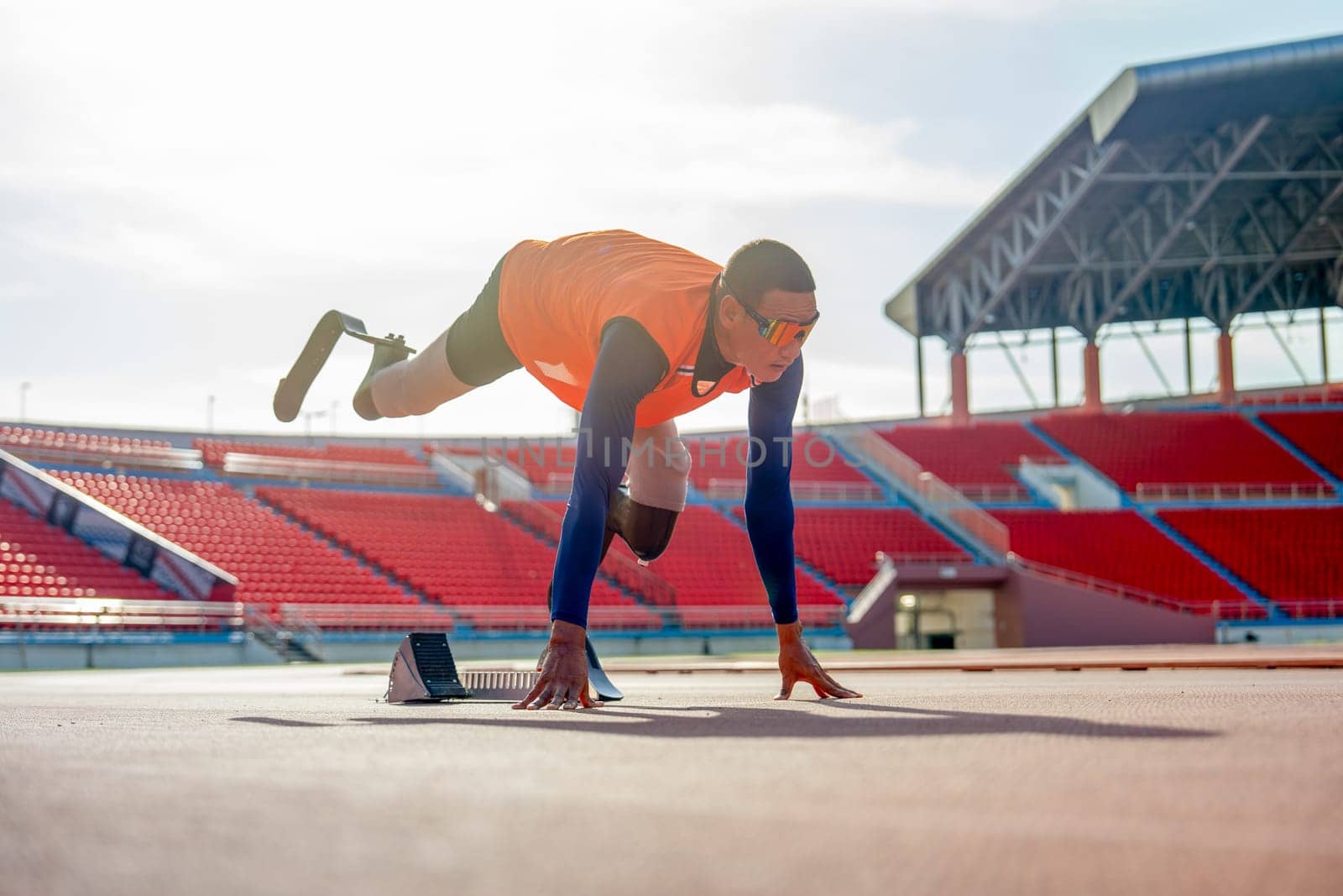 Sport man athlete with a prosthesis on his leg lie down and action of stretch one leg back and up also look forward to warm up before exercise at the stadium.