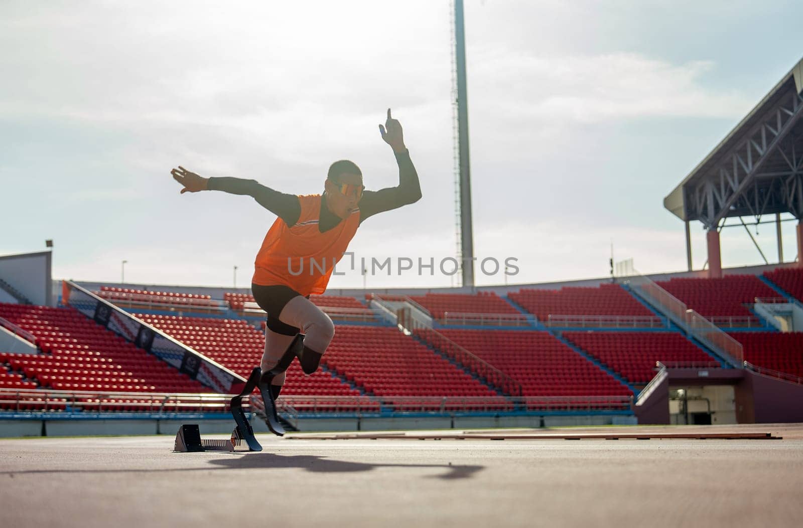 Sport man athlete prosthesis legs start run with look forward at the stadium with soft light of evening.