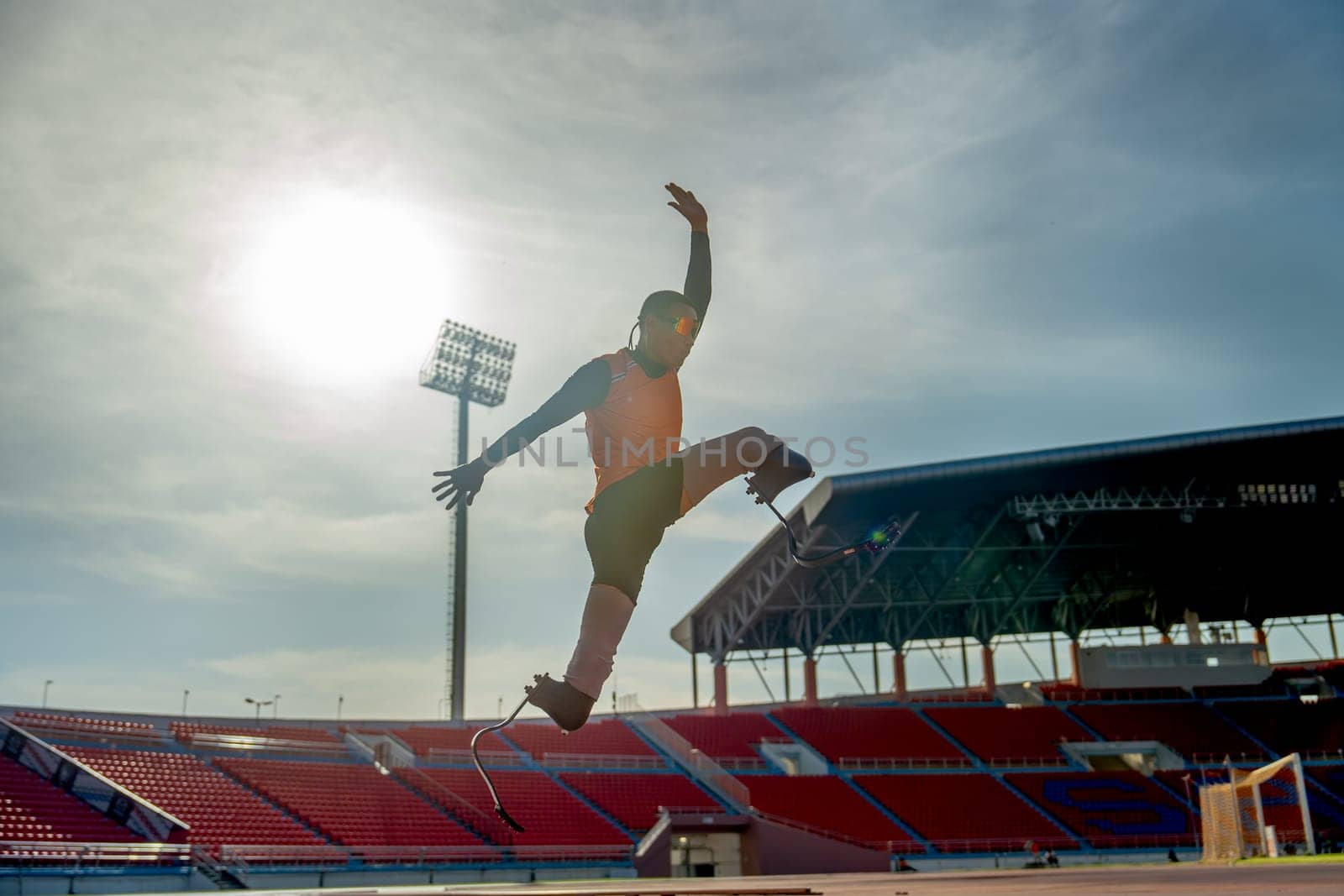 Front view of sport man athlete prosthesis legs jump up in front of sun light in the afternoon of the stadium.