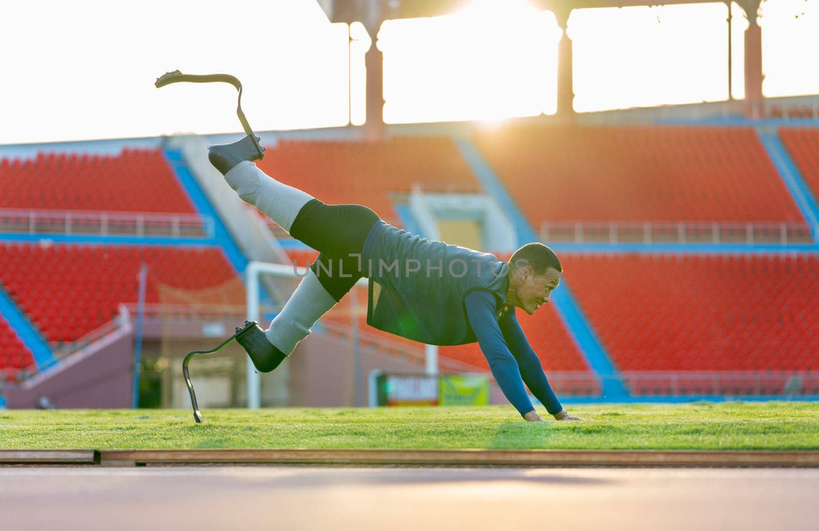 Side view of sport man athlete with a prosthesis on his leg lie down and action of stretch one leg back and up also look forward to warm up before exercise at the stadium.