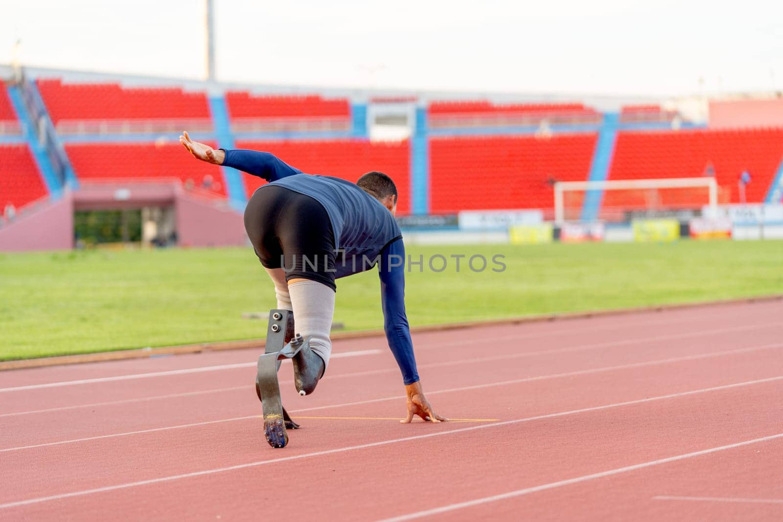 Back of Sport man athlete prosthesis legs run on the track in the stadium with day light.