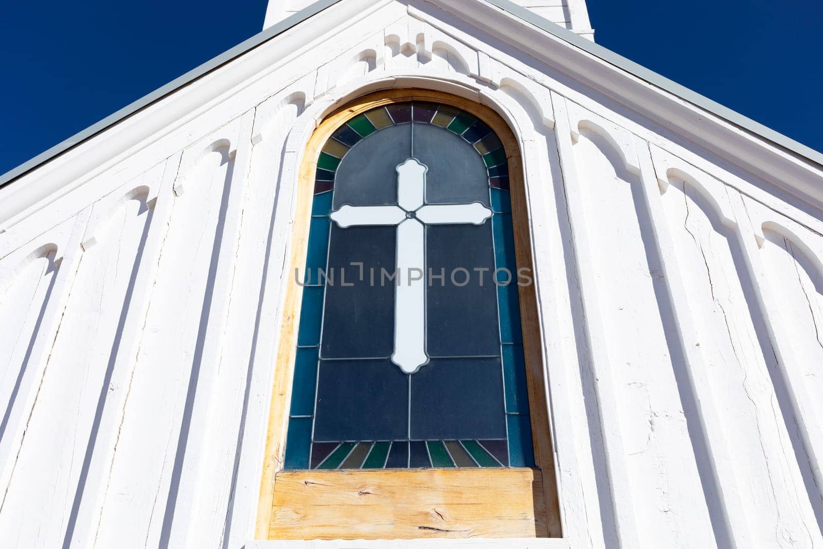 Wooden White Church Stained glass window with Cross, Blue Sky On Background. Christian Religious Holiday Easter or Radonitsa. Horizontal Plane. High quality photo