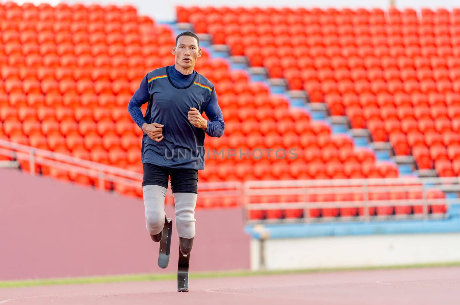 Front view of sport man athlete prosthesis legs is jogging on track in the stadium to practice before copetition in the big event.