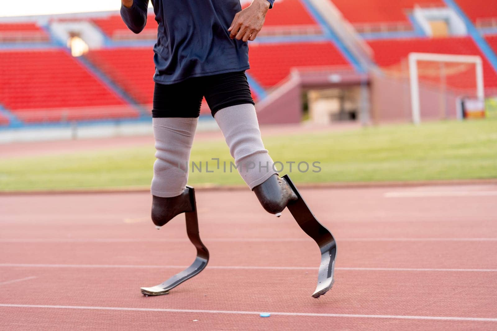 Close up sport man athlete prosthesis legs stand and warm up legs on track in the stadium.