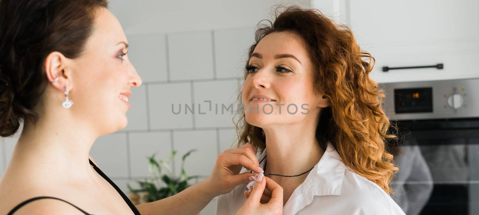 Two cheerful woman enjoying shopping together jewellery boutique. Sister giving present jewelry pendant.