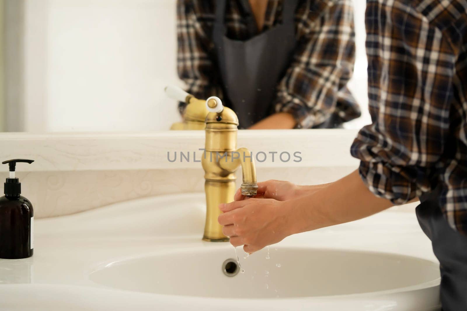 The girl creates cleanliness in the bathroom, cleans her spacious comfortable house using detergents, the woman washes her hands with soap near the mirror.