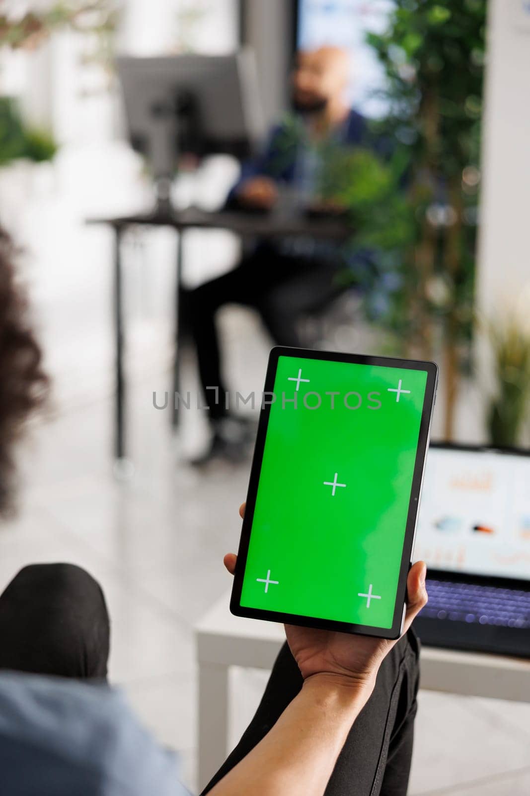 Entrepreneur holding tablet with chroma key screen to chat in video call in coworking space. Company employee using digital device with green touchscreen in business office