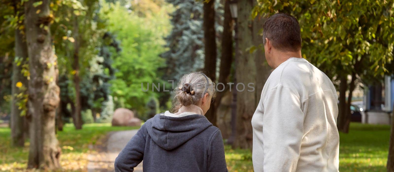 An elderly couple, man and woman walk in the autumn park. by africapink