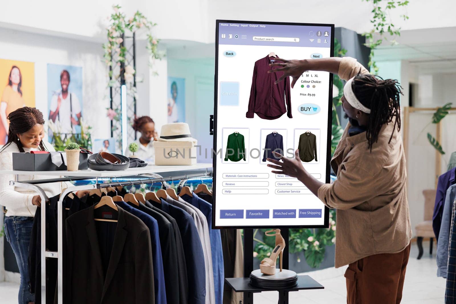 Male customer using clothing store kiosk service, choosing fashion collection items online on self ordering checkout board. Young adult slectiong clothes on interactive monitor display.