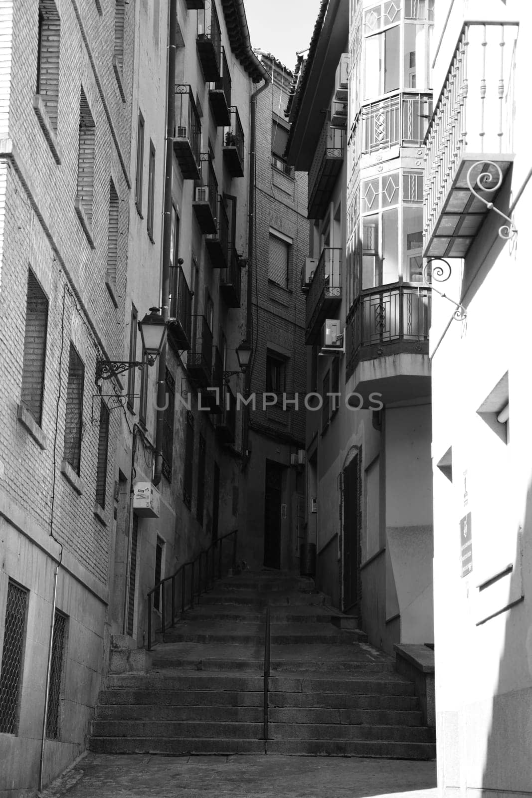 Vertical black and white shot of stairs between two houses in Toledo, Spain