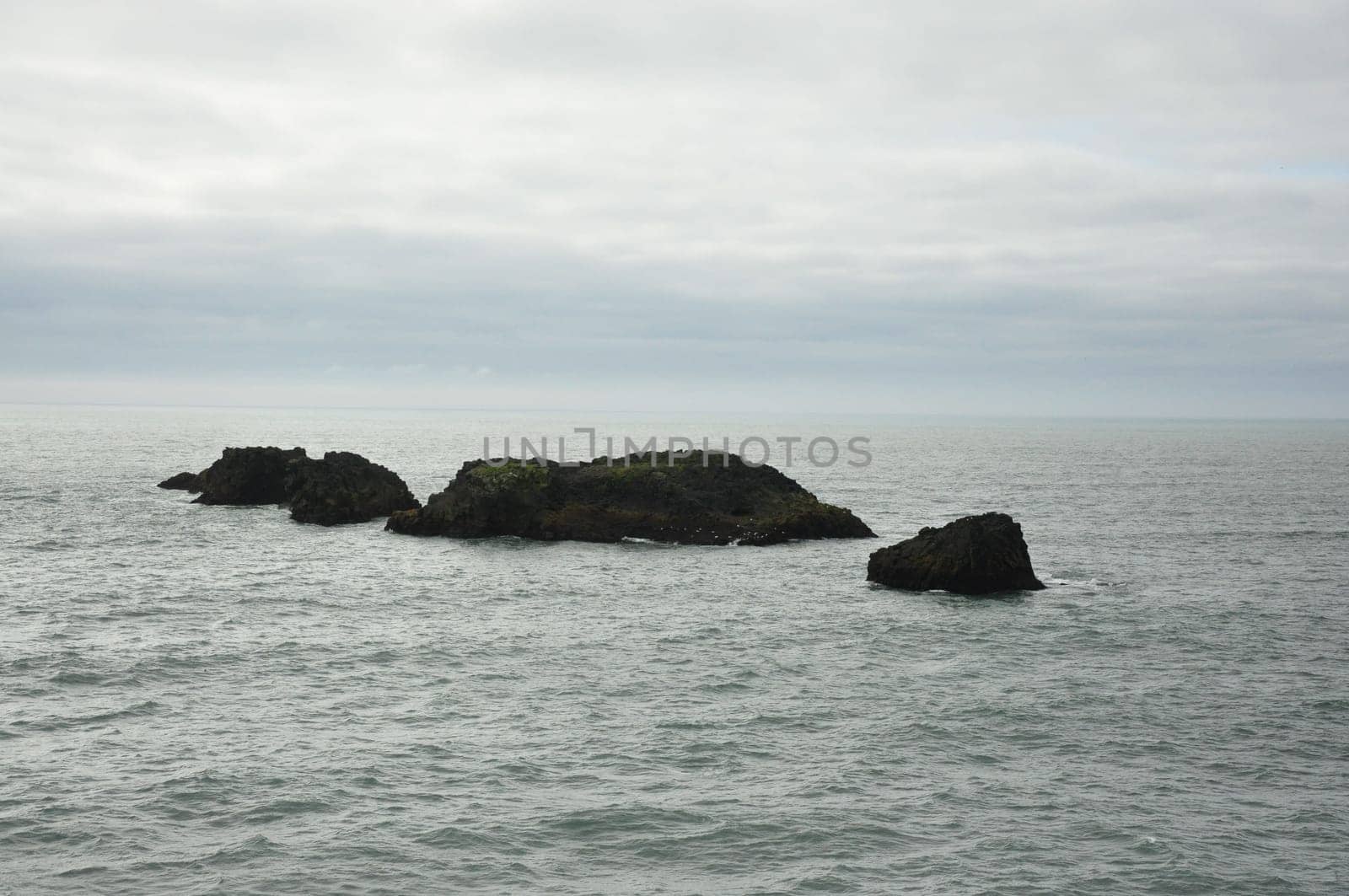 Scenic view of Icelandic peninsula with waves hitting black rocks at overcast Dyrholaey Cape