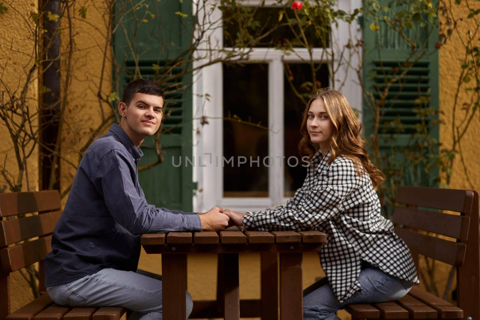 Teen Sweethearts: Holding Hands at an Outdoor Café in a European Town by Andrii_Ko