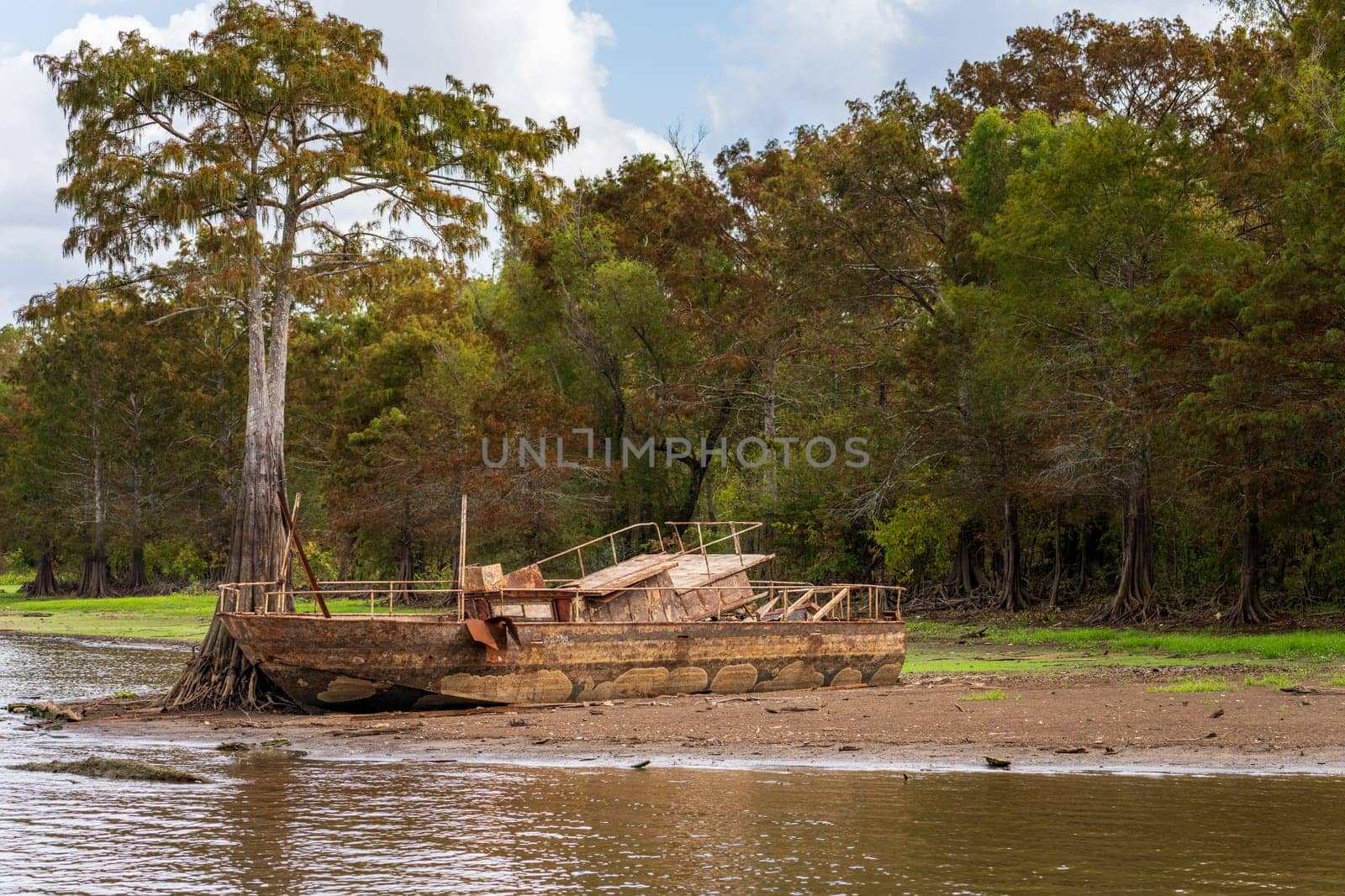 Rusting abandoned boat on the banks by calm waters of the bayou of Atchafalaya Basin near Baton Rouge Louisiana