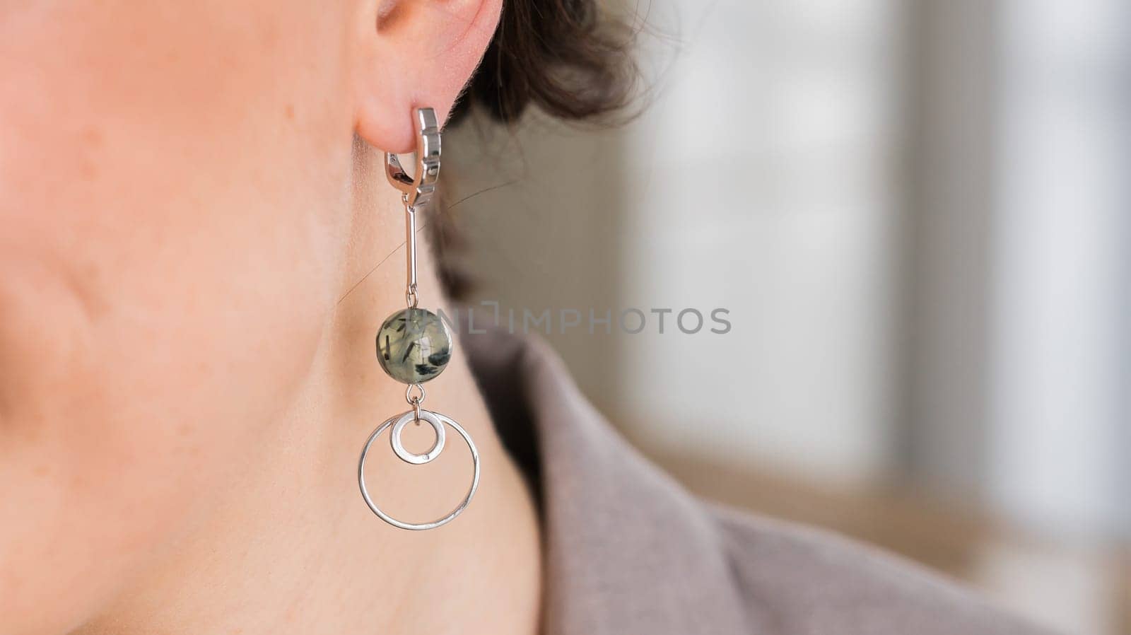 Detail of young woman wearing beautiful luxury earring close-up. Handmade jewellery and accessories. Copy space and empty space for text by Satura86