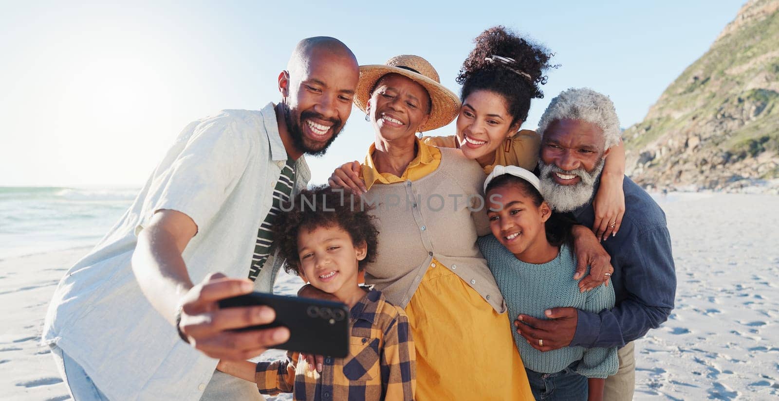 Love, selfie and happy family at a beach for travel, fun or adventure in nature together. Ocean, profile picture and African kids with parents and grandparents at the sea for summer, vacation or trip by YuriArcurs