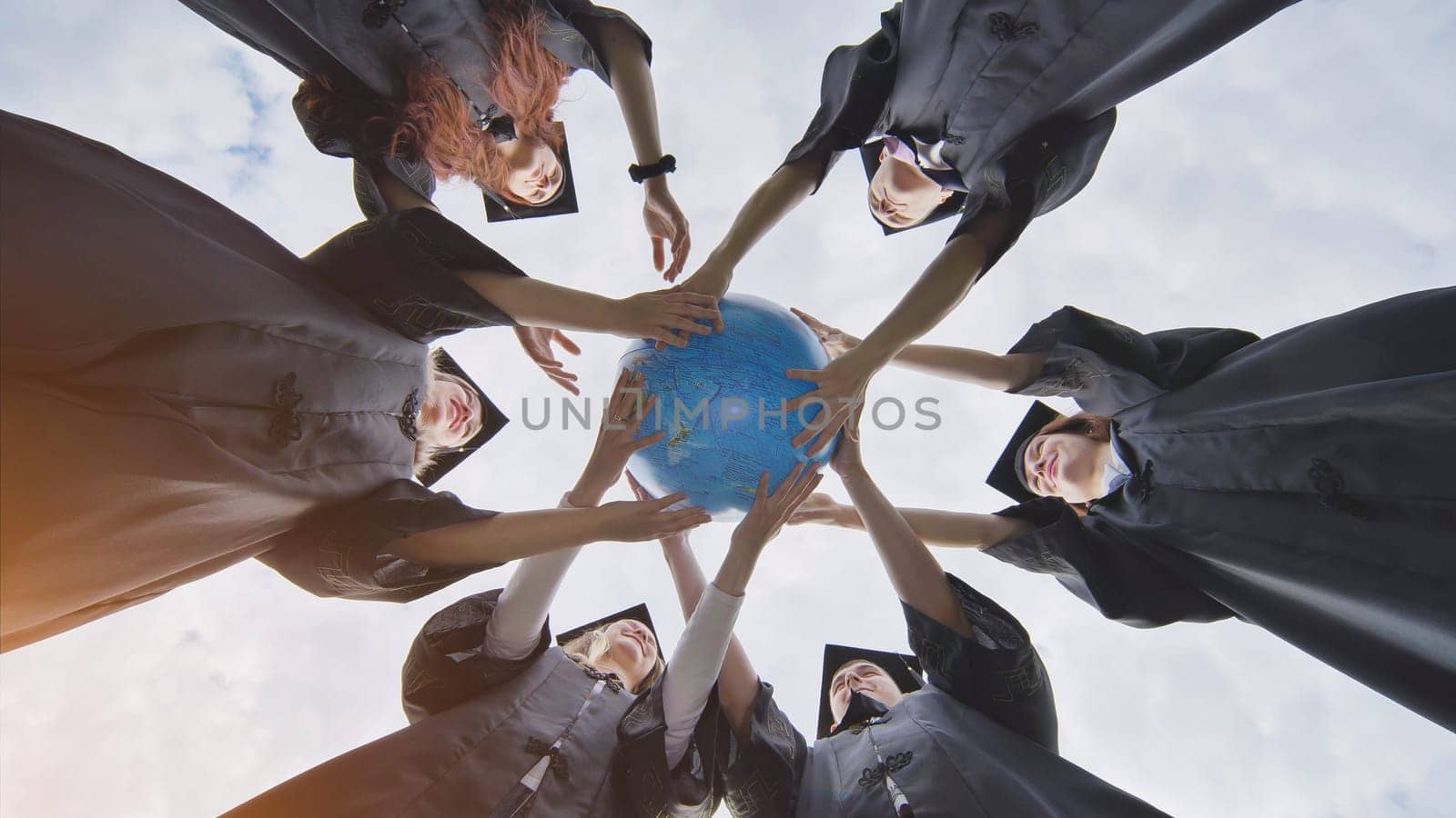 Graduating students twirl a geographic globe of the world in their hands