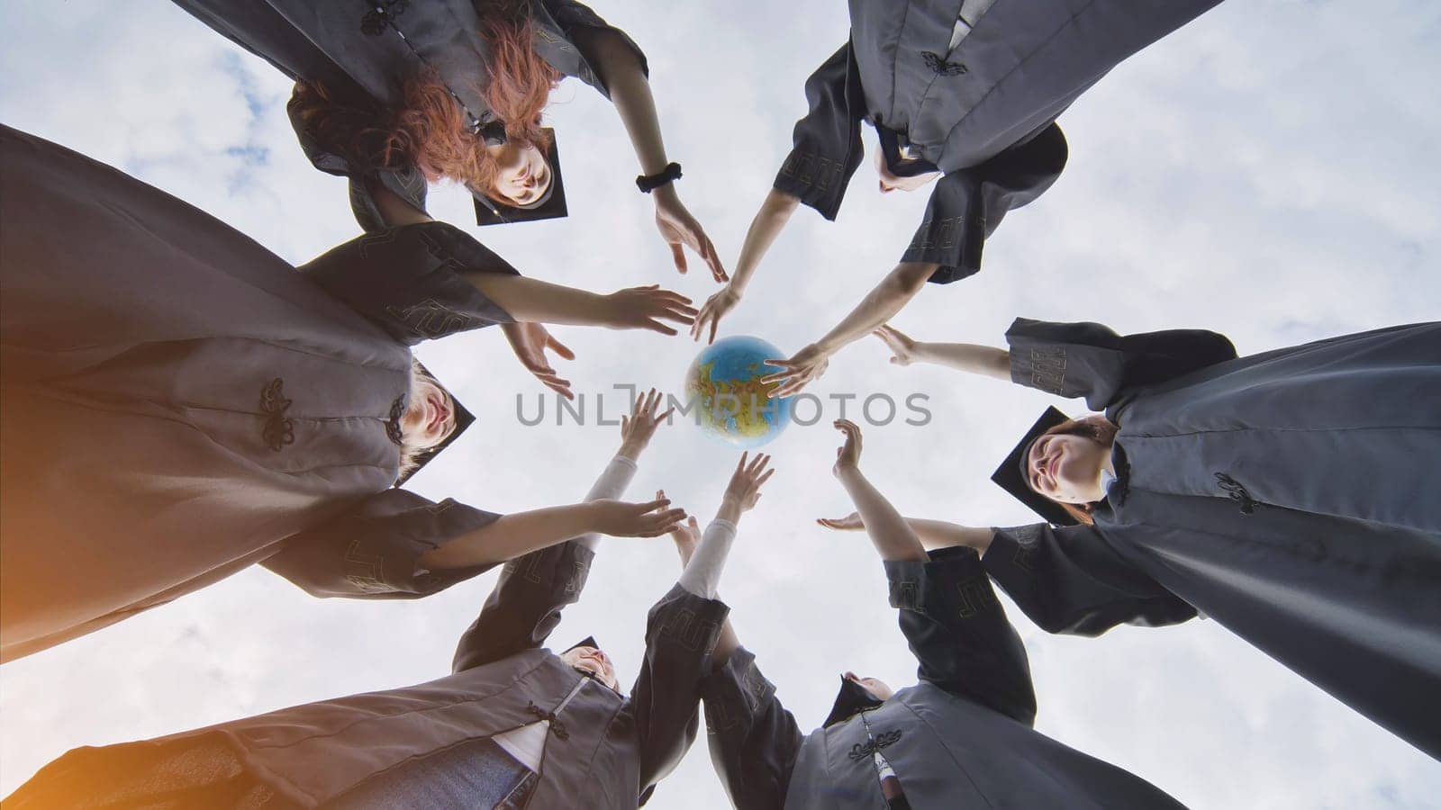 College alumni students toss a globe of the world into the sky