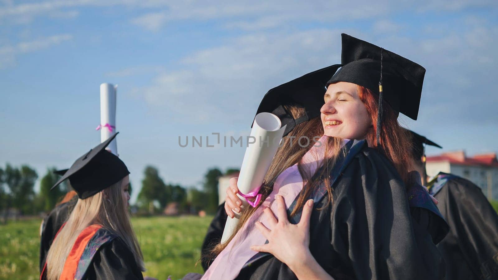 Two college graduates girls hugging on a sunny day