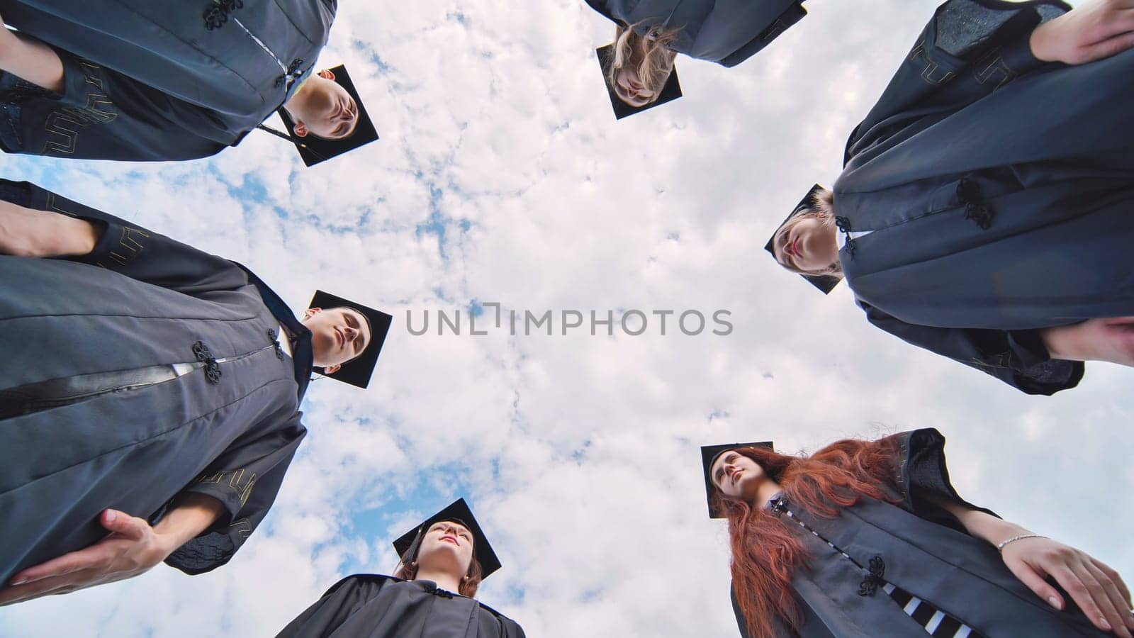 College students stand in a circle wearing black robes. by DovidPro