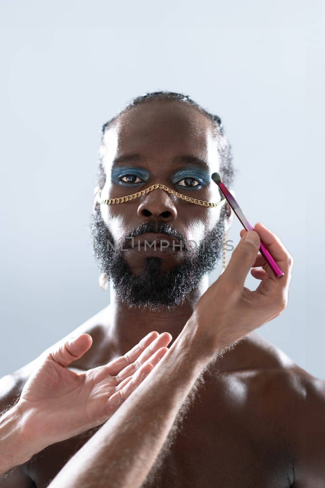 Black gay wearing make-up and hands makeup artist holding make up brush. Close up portrait homosexual man looking at camera ready for apply visage on face. Fashion lgbt concept.