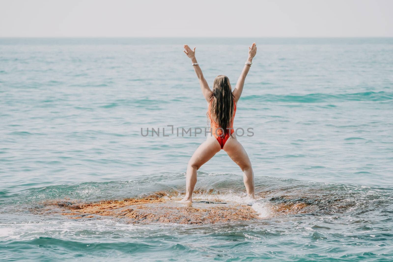 Woman sea yoga. Back view of free calm happy satisfied woman with long hair standing on top rock with yoga position against of sky by the sea. Healthy lifestyle outdoors in nature, fitness concept.