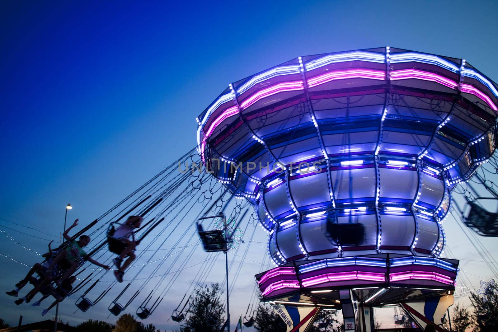 Evening shot of moving amusement park attractions by fotografiche.eu