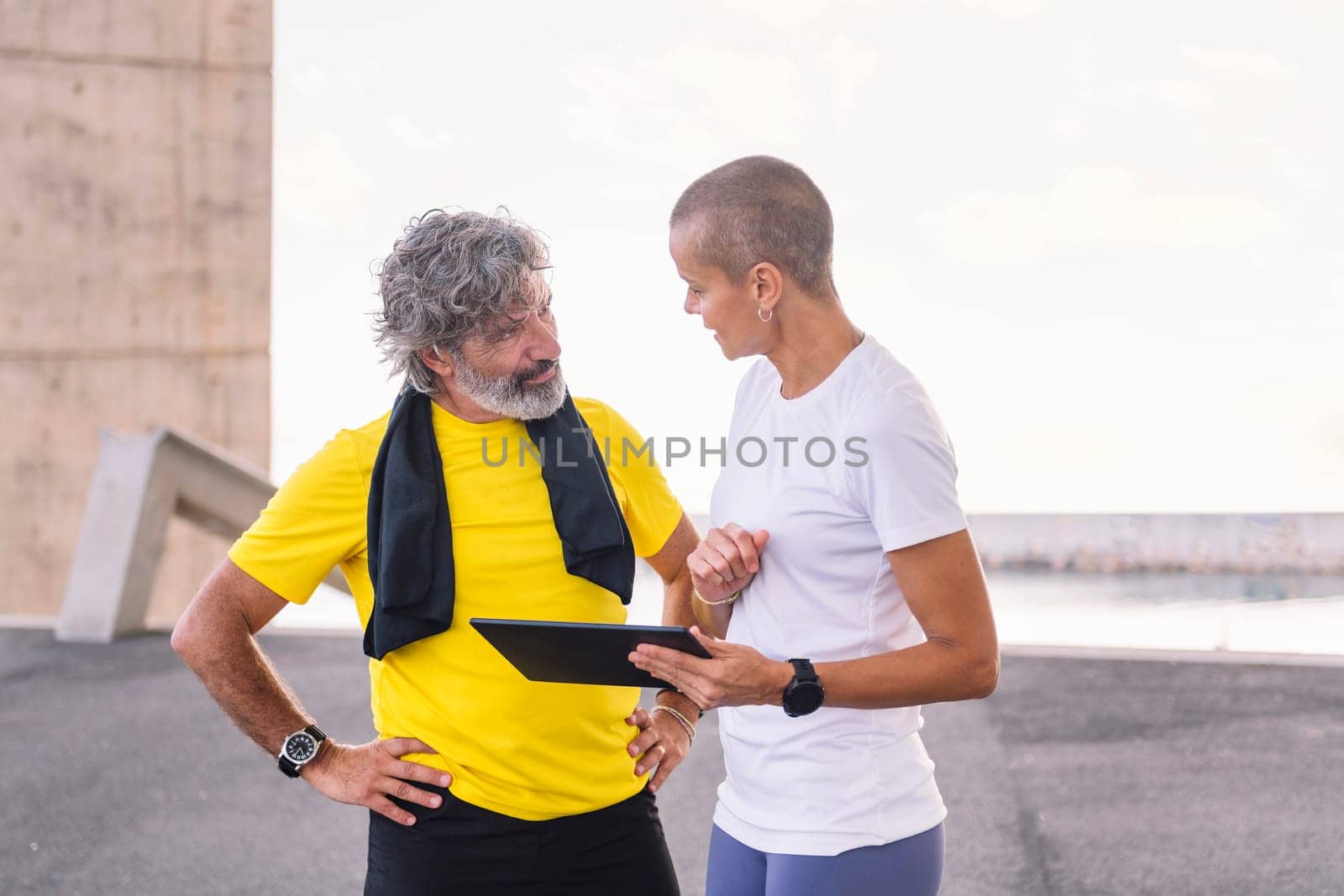 trainer explaining training with tablet to old man by raulmelldo